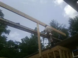 Carpenter setting a ridge beam over a new addition frame — Ice Dam Removal by Roofing Brothers in Leesville