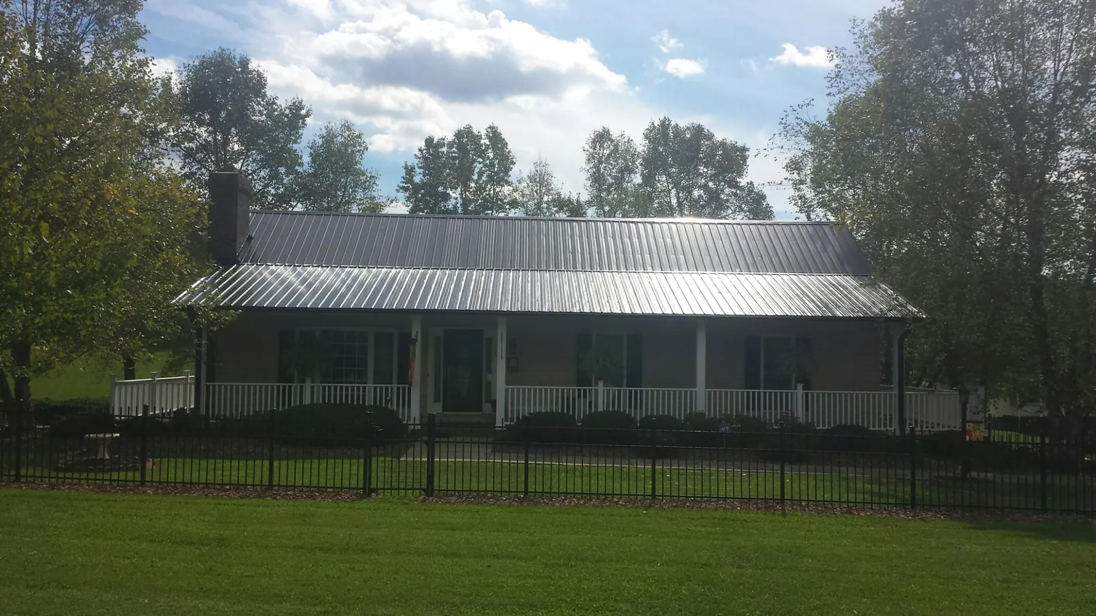 Gray metal roof on a brick ranch with a full width front porch — Gutter Guard Installation work by our crew in Leesville