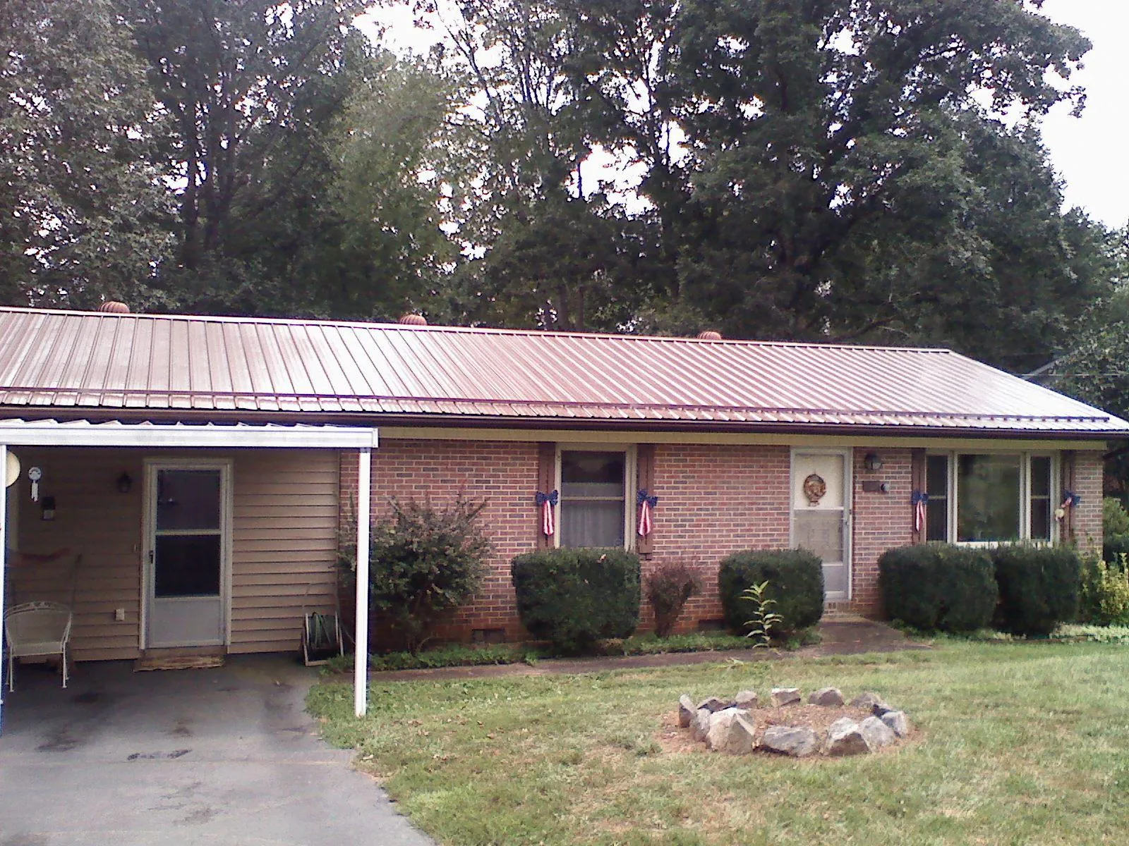 Bronze metal roof and carport on a brick ranch home — Roof Repair work by our crew in Leesville