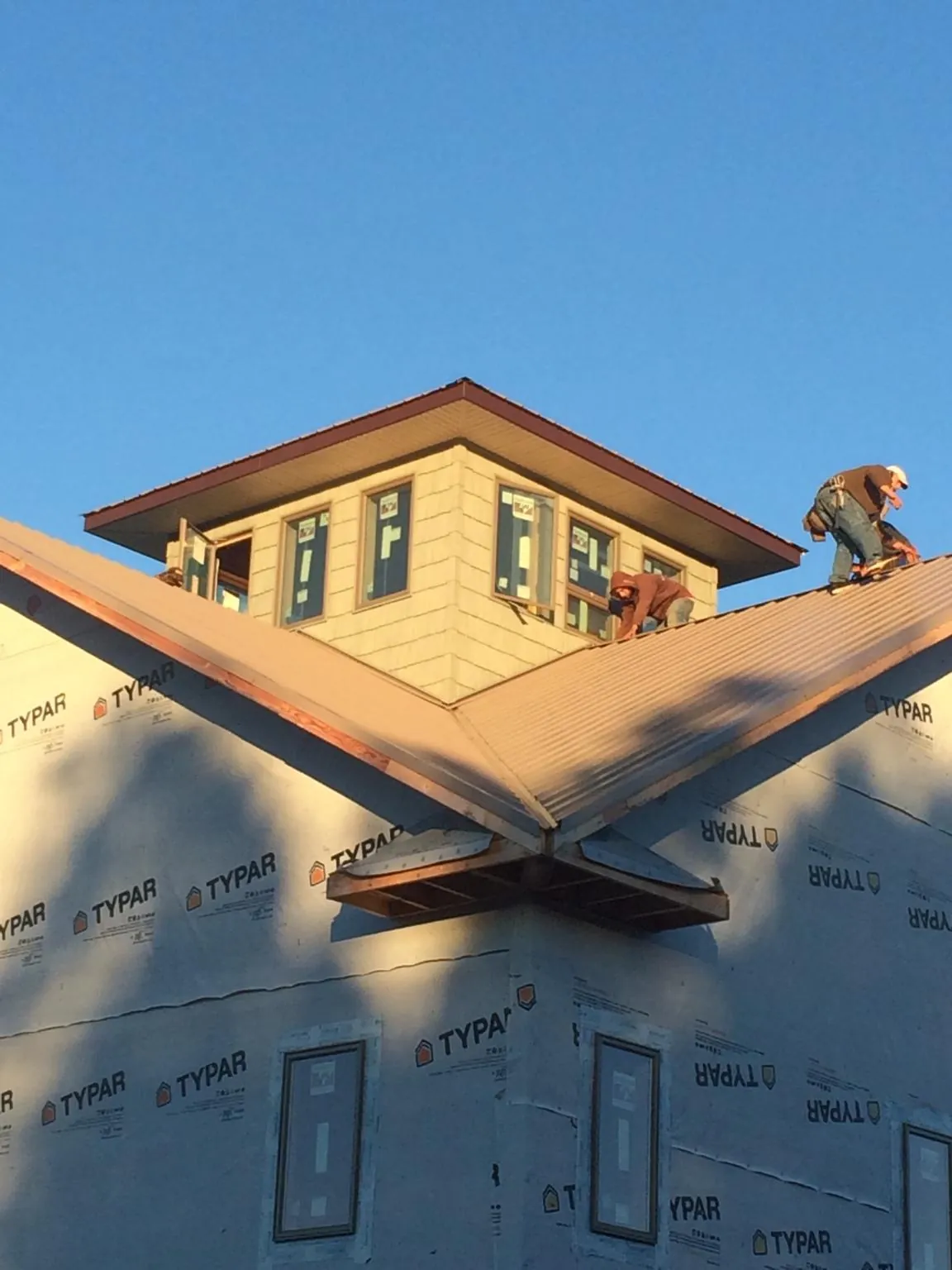 Roofers working around a rooftop cupola on a new metal roof at sunset — Roof Waterproofing in Leesville by Roofing Brothers